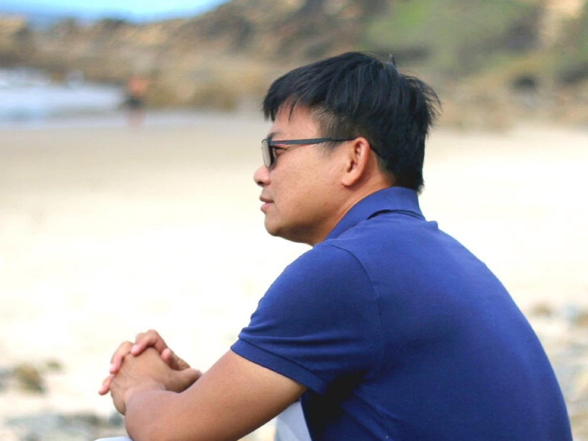 Dr Phong Vo, founder of Sinvesta Group, sitting on the beach looking out to sea.