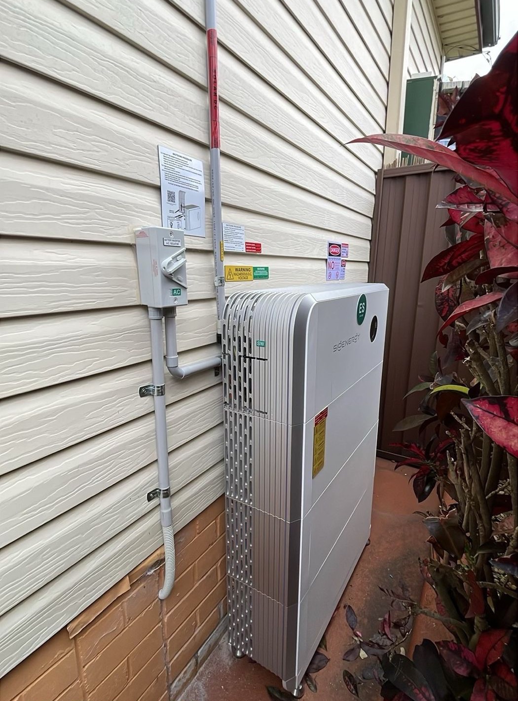 A three-module SigEnergy SigenStor battery installed on an outside wall.