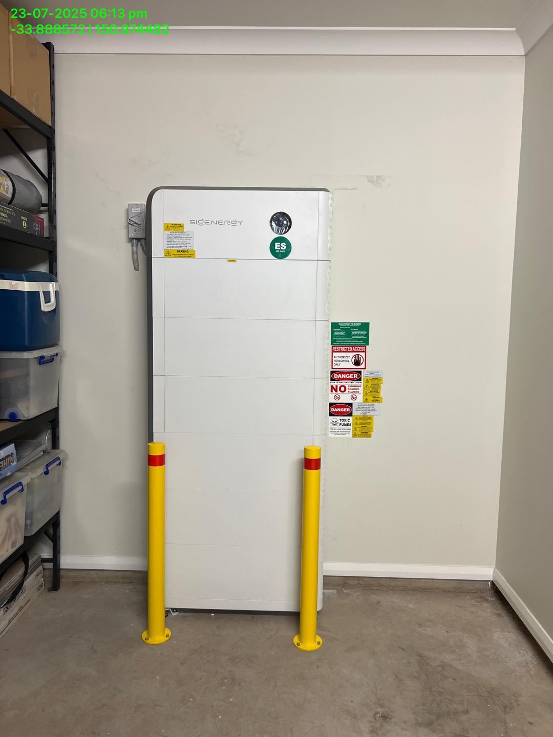 Sigenergy SigenStor battery in a garage with two yellow bollards in front of it.