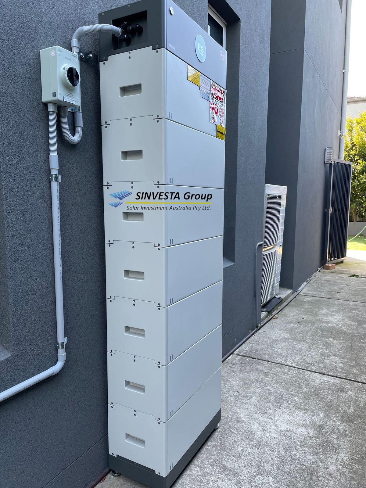 Tall stacked battery system installed beside a home.