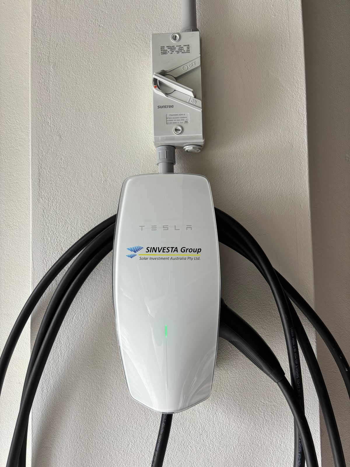 A Sinvesta-installed Tesla Wall Connector EV charger with its cable coiled.