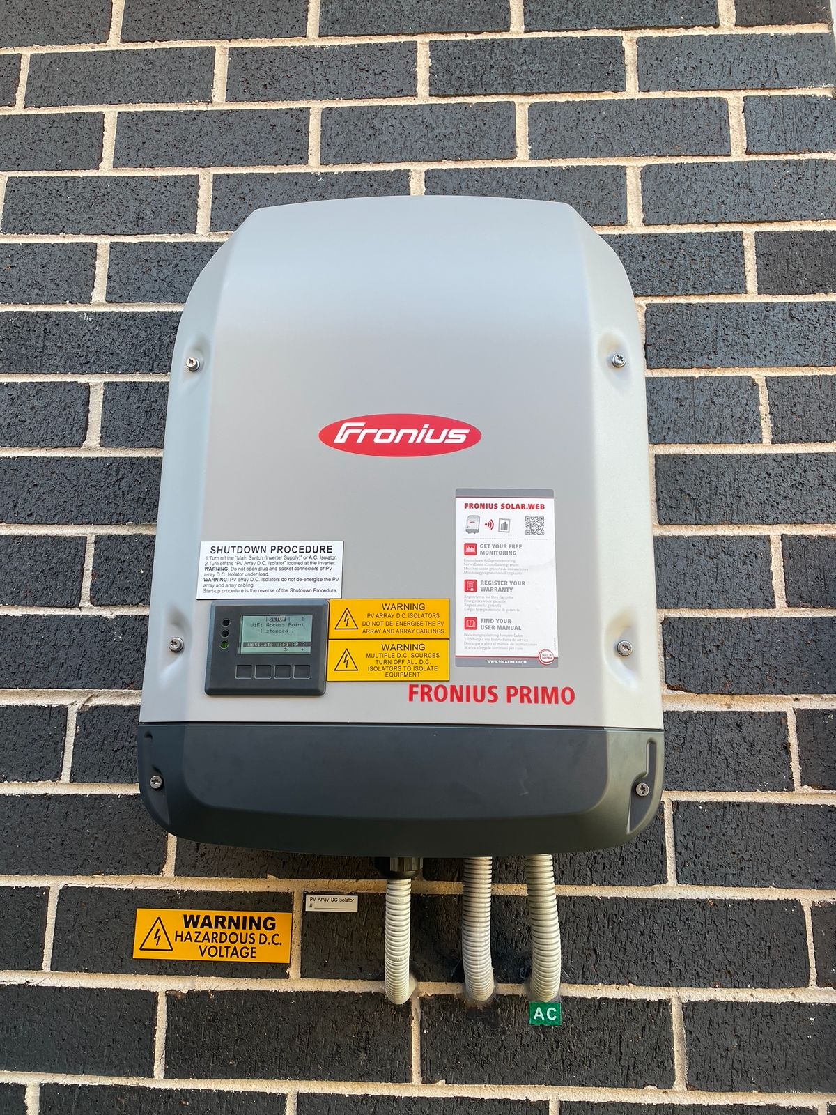 Fronius Primo inverter wall-mounted on brickwork.